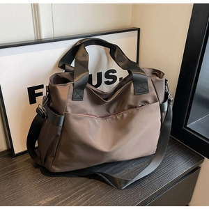 Détail du sac de voyage en nylon marron avec poche zippée et bandoulière robuste