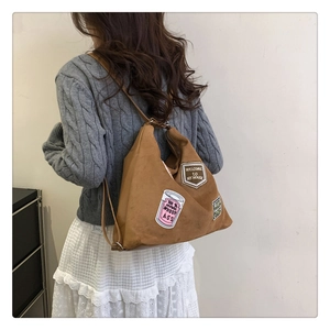 Detail view of brown suede hobo bag with vintage embroidery patches and slim shoulder strap