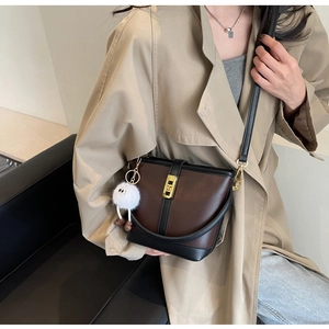 Detail of vintage brown and black bucket bag with gold clasp and plush charm on trench coat