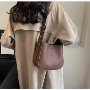 Sac seau en cuir marron avec bandoulière réglable et grand espace intérieur sur modèle