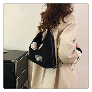Detail of black canvas hobo bag featuring retro colorful embroidered patches and lettering