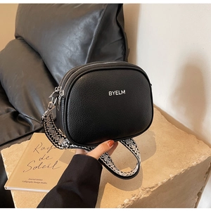 Detail view of black pebble leather crossbody bag with ethnic patterned wide strap