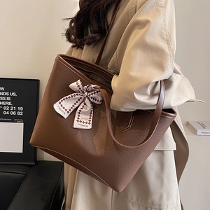 Brown leather tote bag with a checkered bow scarf on a model wearing a beige trench coat