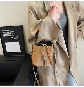 Détail d'un sac seau en daim kaki avec logo NY métallique et bandoulière en cuir
