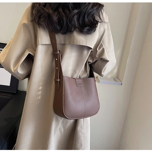 Détail du sac seau en cuir grainé marron avec lettrage mode et bandoulière réglable