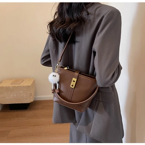 Brown leather bucket bag with gold buckle and plush eyeball charm shown from back view