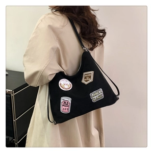 Detail of black canvas tote bag featuring vibrant colorful embroidered patches on the side