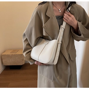 Détail d'un sac seau en cuir blanc à motif litchi porté avec un trench-coat kaki