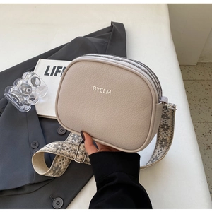 Detail of beige lychee texture leather crossbody bag with three zip pockets and wide strap