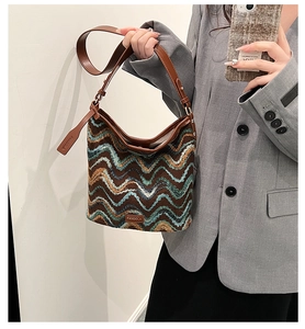 Detail of knit hobo bag featuring wavy pattern in brown and blue with leather strap