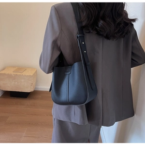 Détail d'un sac seau en cuir grainé noir avec bandoulière réglable porté par un mannequin