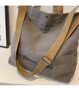 Detail of adjustable khaki woven shoulder strap on a taupe canvas tote bag