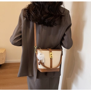 Detail view of retro leather bucket bag with contrast trim and gold twist lock closure
