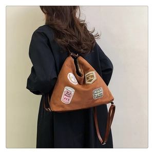 Detail of vintage brown suede backpack featuring unique retro embroidered patches and leather strap