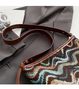 Detail of bohemian knit bucket bag with wave patterns and a brown leather shoulder strap