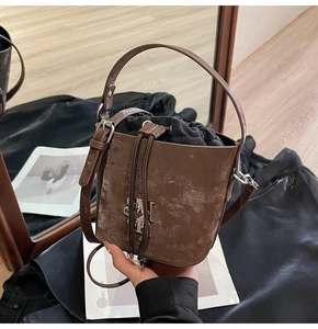 Détail du sac seau vintage marron avec texture usée et logo métallique SMT