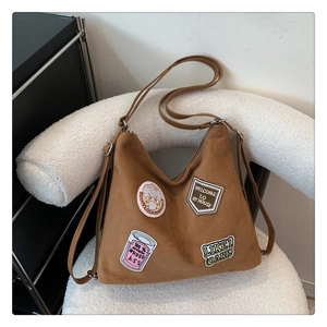 Detail of vintage brown tote bag featuring unique cartoon patches on a textured surface