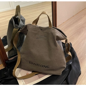 Detail view of brown canvas tote with adjustable strap and metallic snap button closure