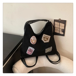 Detail of black suede tote with retro embroidery patches and versatile strap design