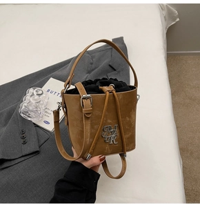 Détail d'un sac seau vintage en cuir marron avec logo en métal et cordon interne