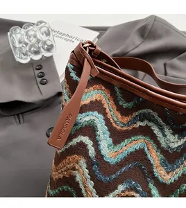 Detail of woven bucket bag featuring wave patterns and brown leather logo tag
