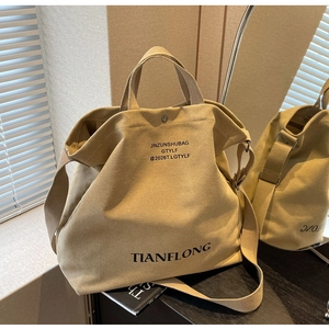 Detail of khaki canvas tote bag with adjustable strap and printed branding on the front