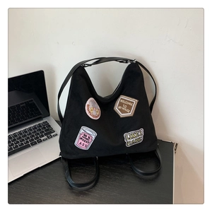 Close-up of black tote bag featuring vintage embroidered patches on a wooden table