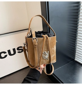 Gros plan du sac seau en daim fauve avec fermeture à cordon et logo argenté élégant