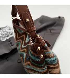 Detail of vintage woven bucket bag with golden studs and brown leather strap connection