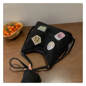 Close-up of black suede tote bag featuring vintage American style embroidered patches