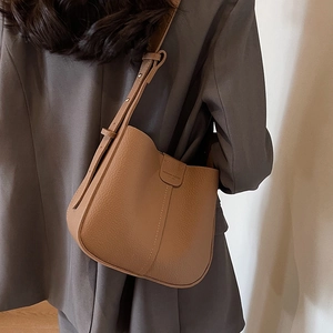 Sac seau en cuir grainé marron avec bandoulière réglable porté à l'épaule