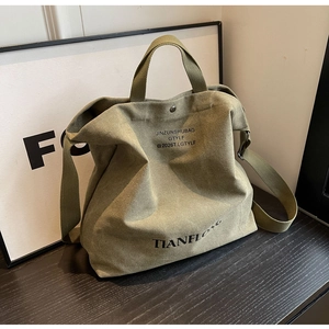 Close-up of army green canvas tote bag showing wide adjustable strap and metal snap button
