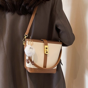 Women's cream and brown bucket bag with gold clasp and decorative white fur ball
