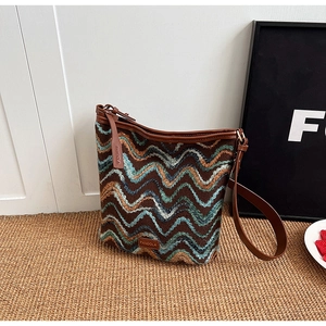 Detail of bohemian knit shoulder bag with colorful zig-zag patterns and leather brand tag
