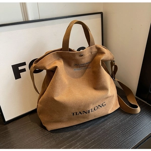 Detail of a brown canvas tote bag featuring metallic snap closure and textured fabric finish