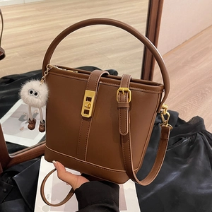 Elegant brown bucket bag for women with gold hardware and a cute plush monster charm
