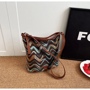 Close-up of bohemian knit bucket bag with brown leather strap and zigzag wave pattern