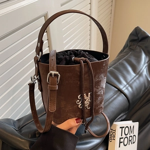 Sac seau rétro marron en cuir texturé avec logo argenté dans un décor élégant