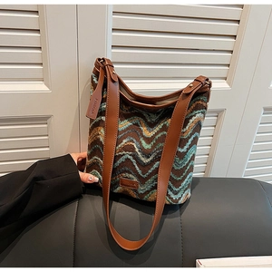 Close-up of knit tote bag with colorful wave patterns and premium leather brand tags