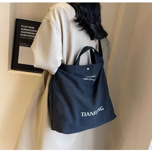 Detailed back view of a woman wearing the black canvas tote bag with shoulder straps