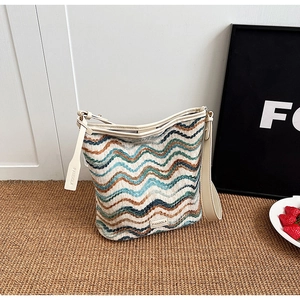 Detail of colorful wavy knit bucket bag featuring cream leather trim and brand tag