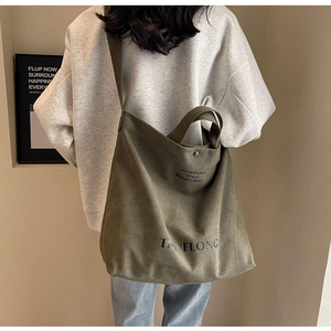 Detail of army green canvas tote bag with letter print and metal clasp closure