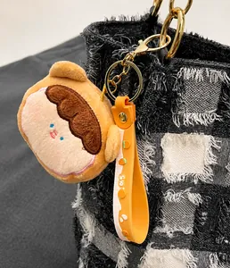 Dettaglio portachiavi in peluche con cinturino arancione su borsa a quadri scacchi