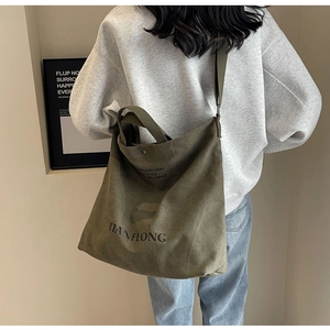 Detail of army green canvas tote bag featuring metal snap closure and durable strap