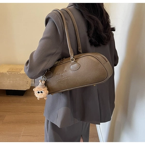 Detail of vintage brown leather bowling bag showing embossed logo and plush charm