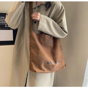 Detail of earthy brown corduroy tote bag showing textured fabric and black letter print
