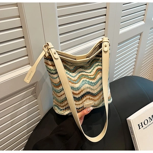 Close-up of knit wave pattern tote bag with leather straps and metallic logo detail
