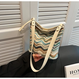 Detail of woven tweed bucket bag with wavy teal patterns and premium leather strap