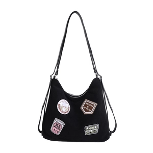 Black canvas tote bag with embroidered patches and shoulder strap for casual street style