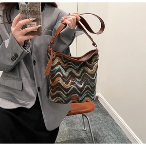 Close-up of wavy knit shoulder bag with brown leather accents and brand name detail